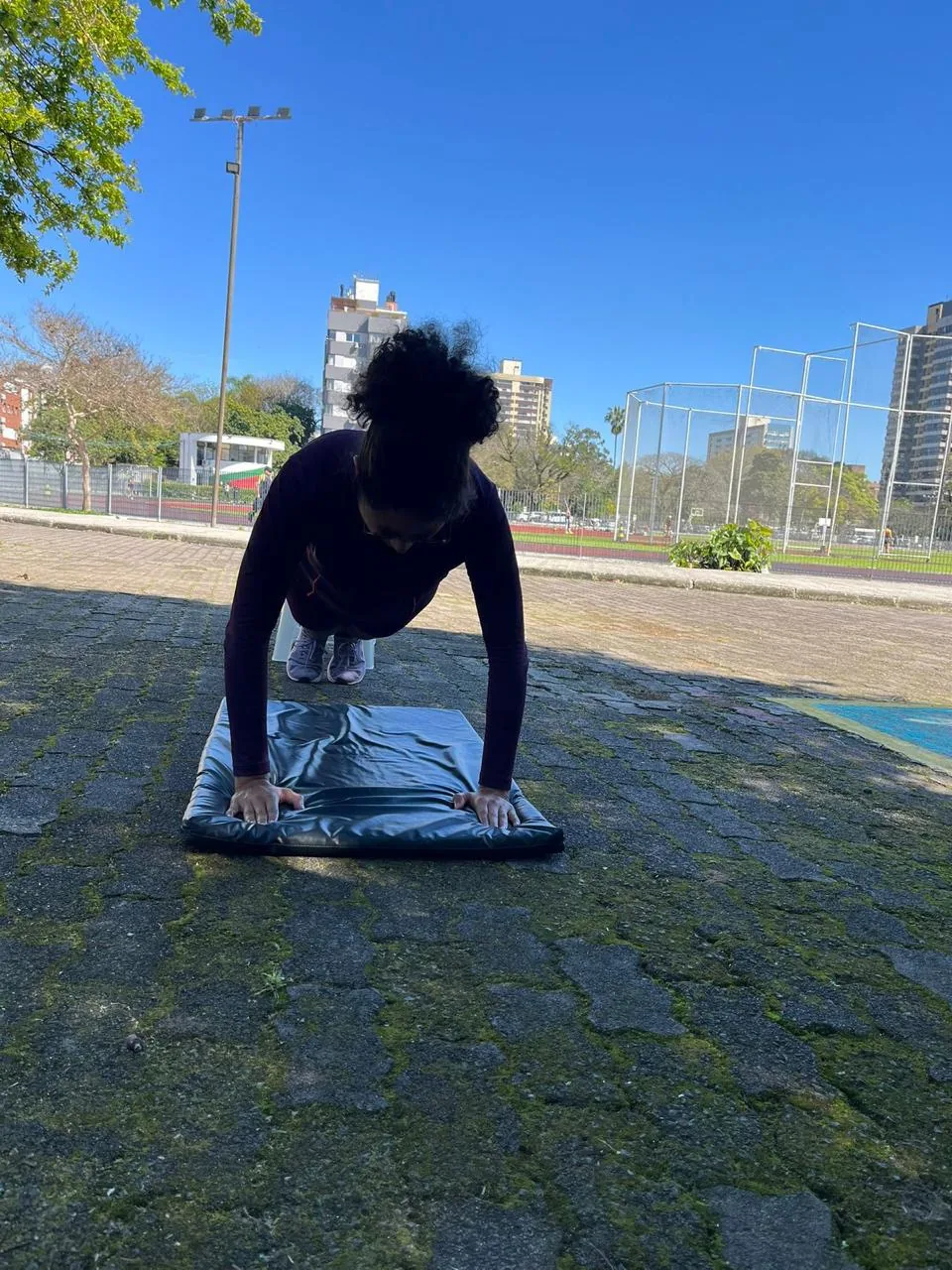 Aluna realizando uma flexão em área externa.